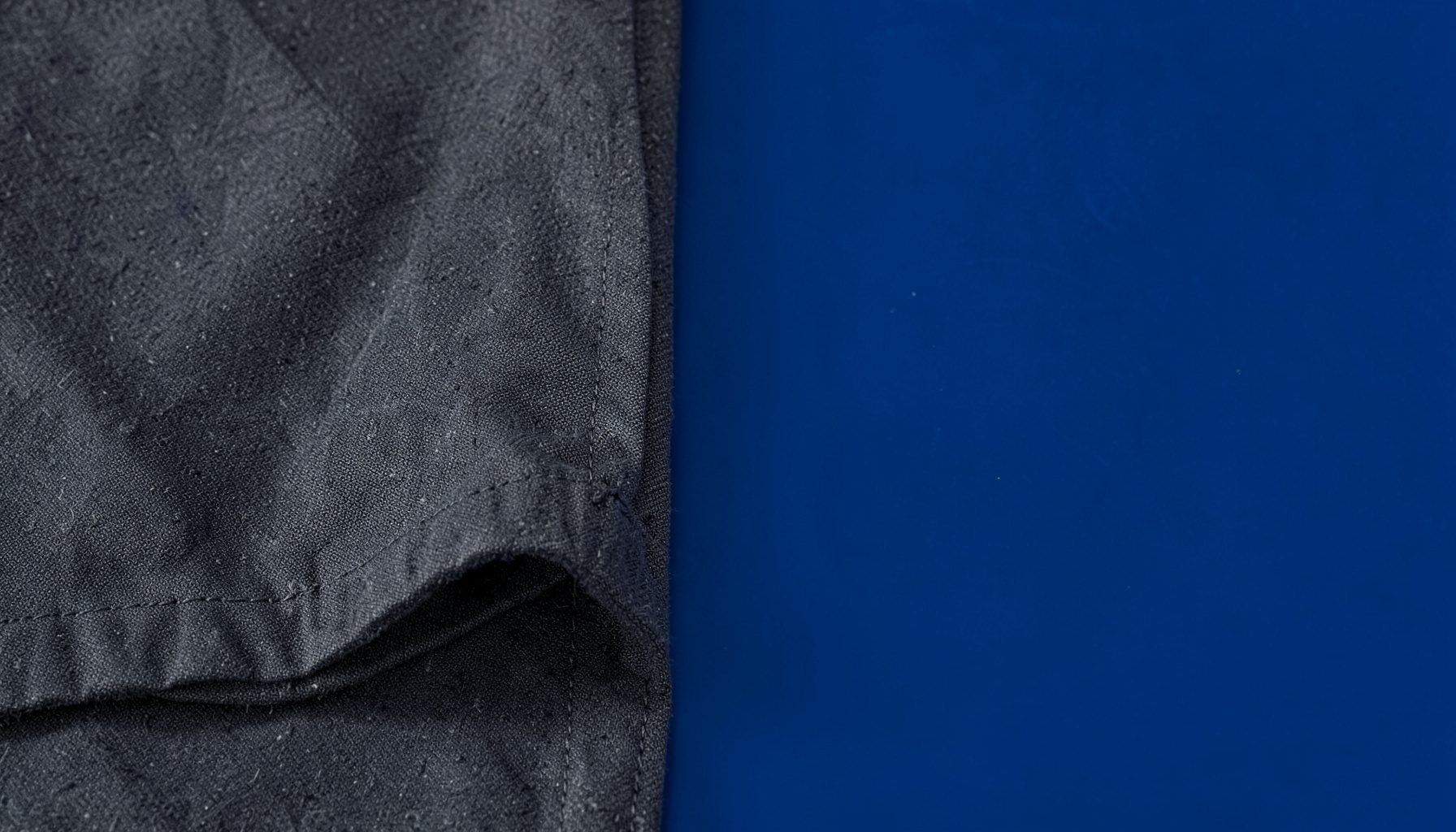 Close-up of charcoal gray fabric with folded edge and visible stitching
