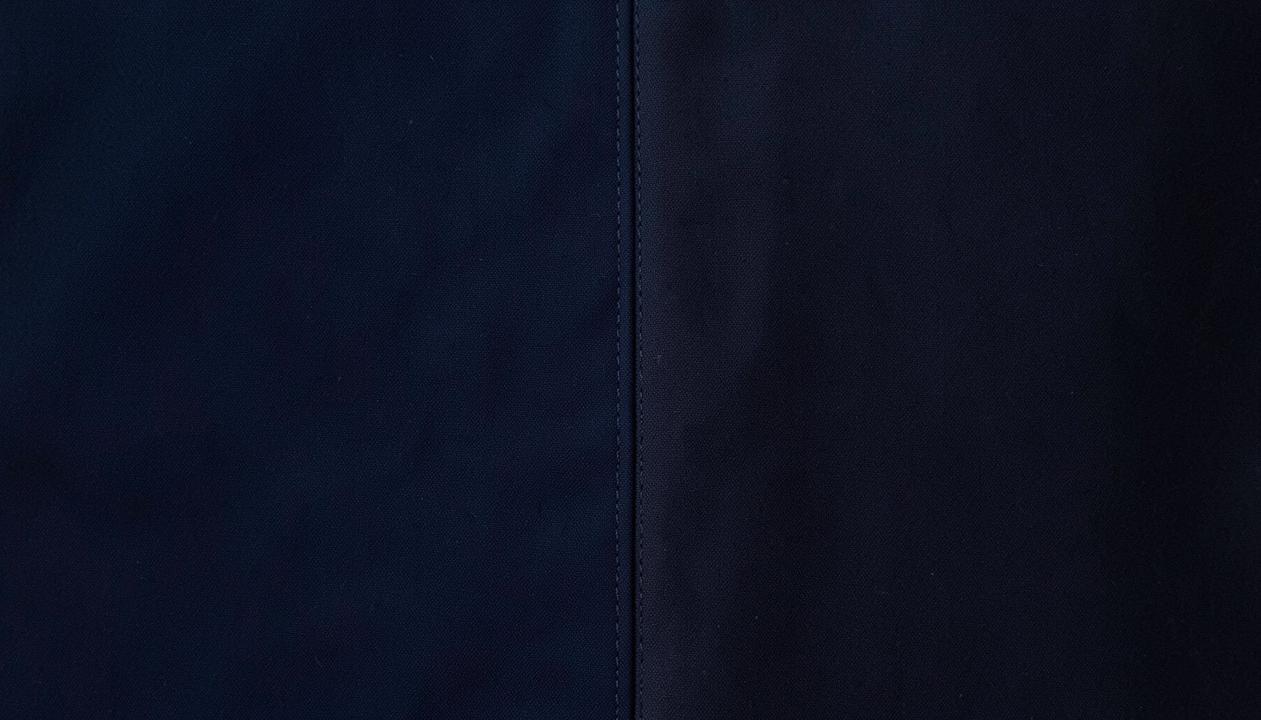 Dark navy and charcoal fabric with subtle stitched seam detail, moody and minimal