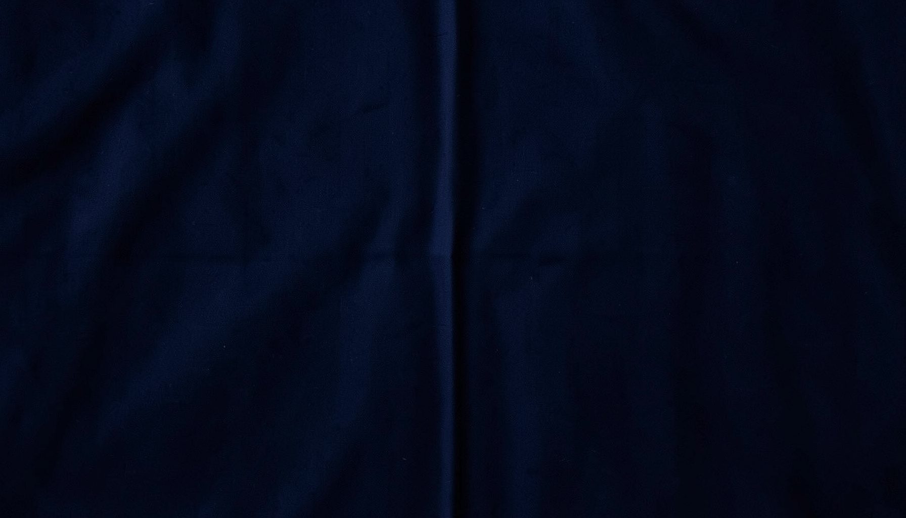 Dark navy fabric surface with subtle folded texture, deep moody atmosphere