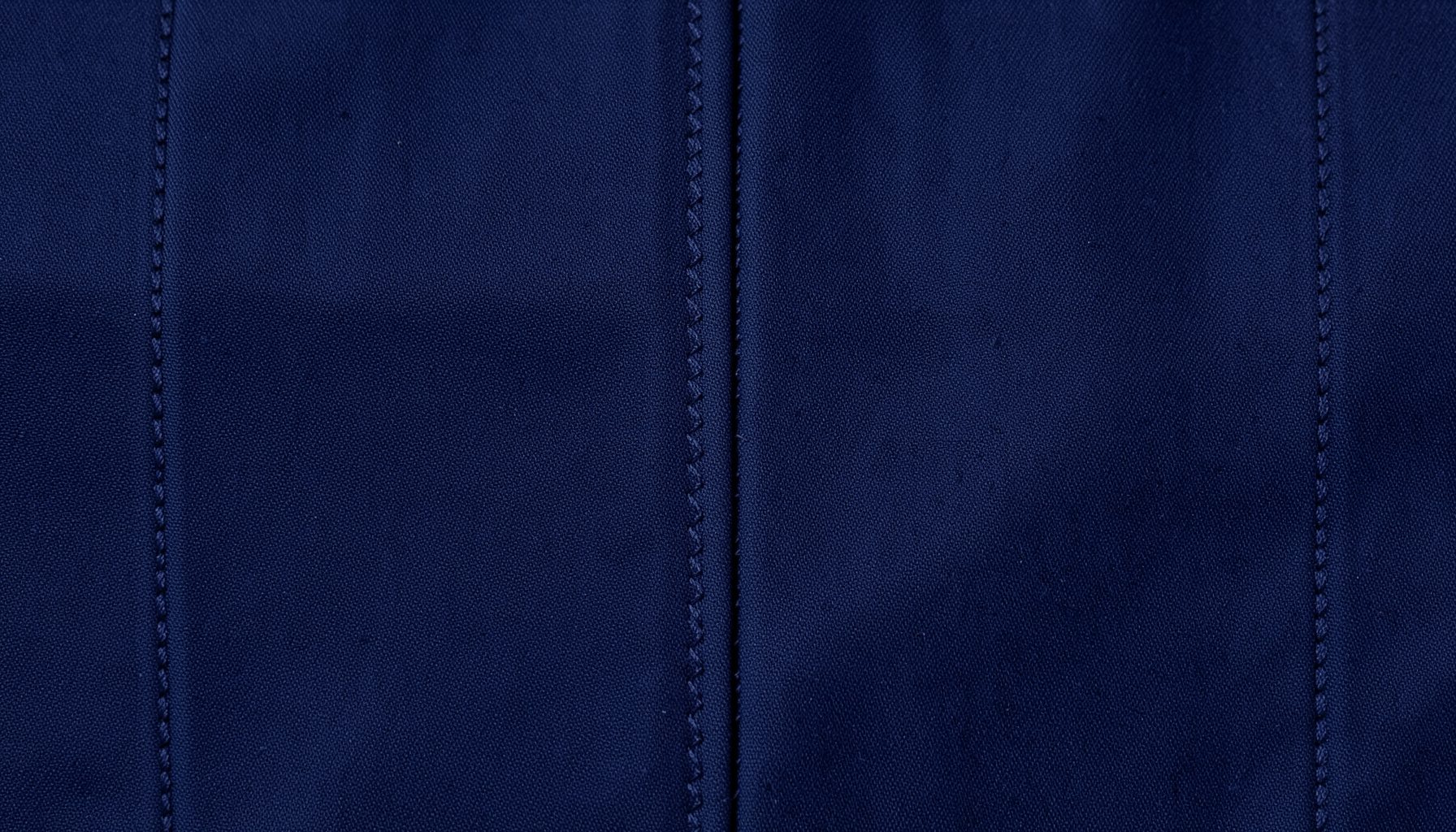 Close-up of dark navy fabric with precise zigzag stitching, clean and structured