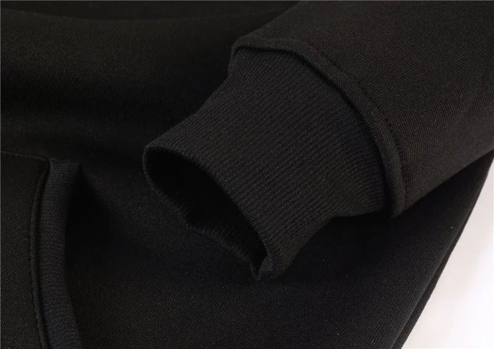 Close-up of black fabric sleeve and pocket detail of a garment, dark monochrome tones