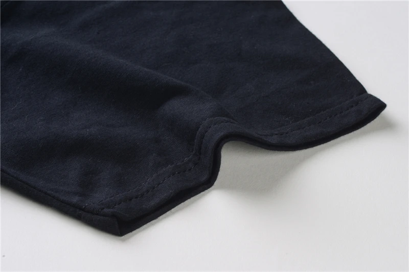 Close-up of dark navy fabric hem with curved stitched seam on white background