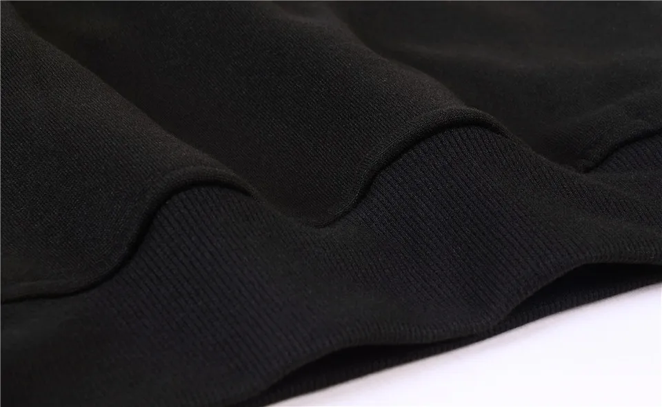 Close-up of folded black fabric with ribbed hem texture, dark and minimal mood